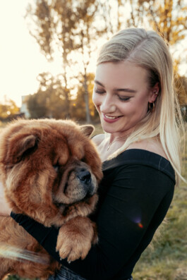  Portrait der Inhaberin mit einem großen Hund auf dem Arm.